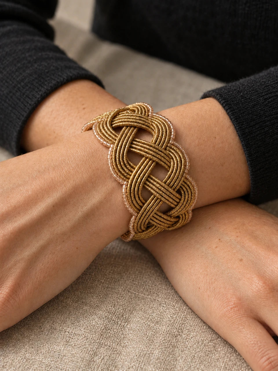 Bracciale intrecciato color oro indossato, immagine editoriale AI